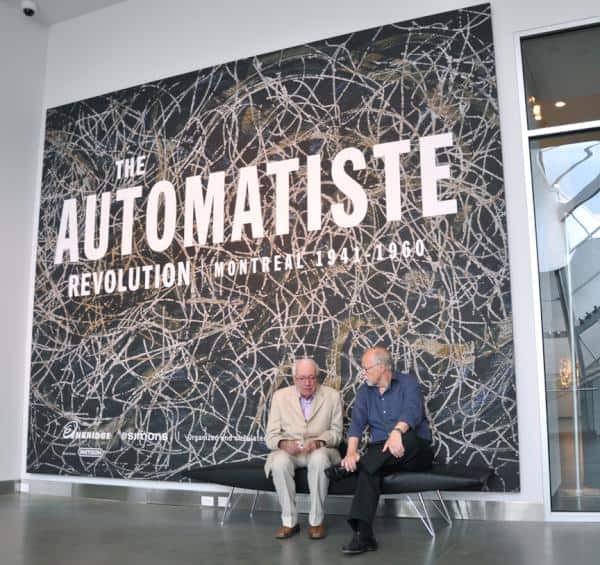 Automatiste artist Marcel Barbeau and Roald Nasgaard, curator in front of the banner of the exhibition The Automatiste Revolution at the AGA in Edmonton.  Represented on the banner : Rosier-Feuilles by Marcel Barbeau. 