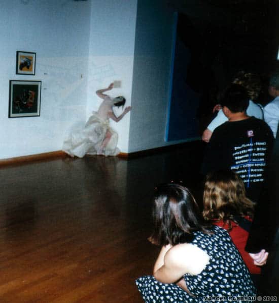 Performance de Jocelyne Montpetit dans l'exposition "Marcel Barbeau Dérive et variations" à l'occasion du vernissage. Maison de la Culture Côte-des-Neiges, Montréal, 28 juin 2000. Photo Françoise Gilbert avec l'aimable permission de cette dernière. © Françoise Gilbert et ADAGP-Paris pour Marcel Barbeau.